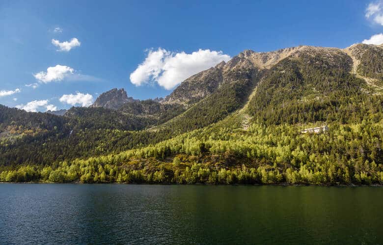 See mit grünen Wäldern und hohen Bergen im Hintergrund