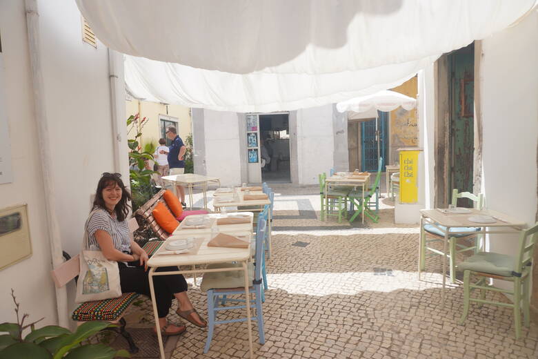 Frau sitzt in einem Restaurant in einer portugiesischen Altstadt