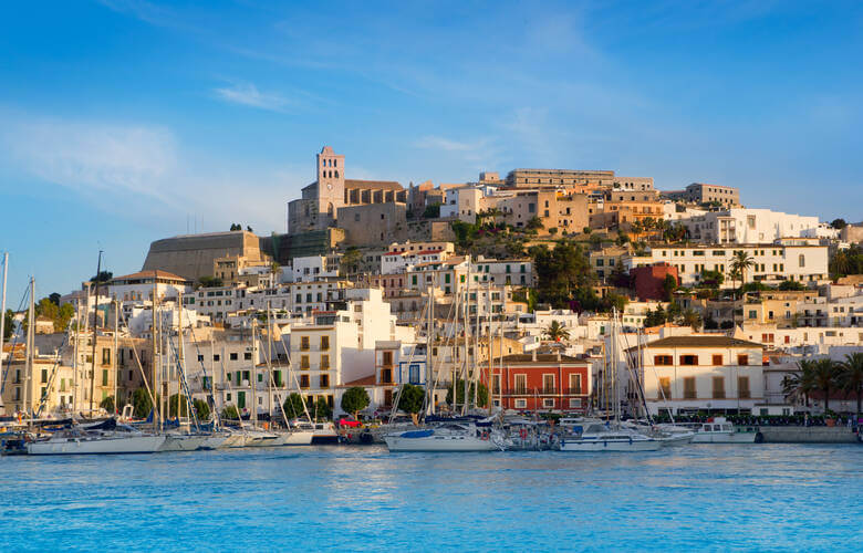 Der Hafen von Ibiza-Stadt (Eivissa) mit dem Stadt-Panorama im Hintergrund und dem blauen Meer im Vordergrund