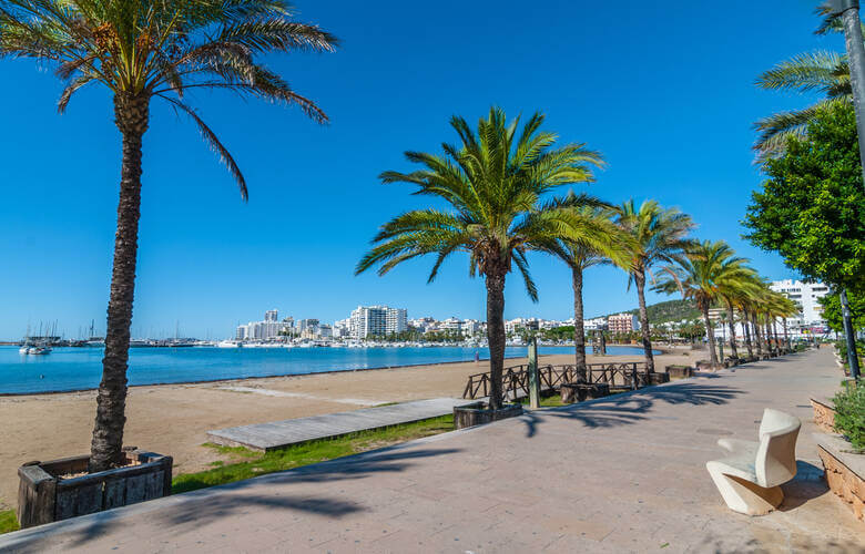 Die Promenade von St. Antoni de Portmany mit Palmen und Ausblick auf Meer und Stadt