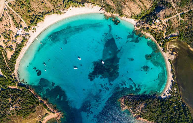 Aufnahme der muschelförmigen Bucht von oben mit blauem Wasser und mehreren Schiffen