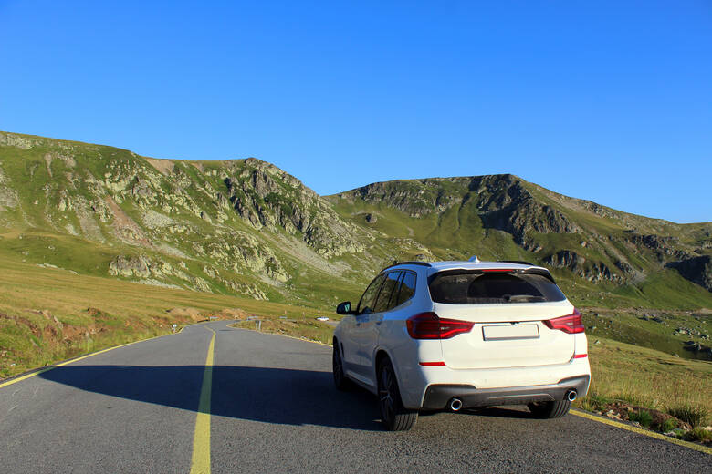 Weißes Auto fährt über eine Straße in den transilvanischen Alpen