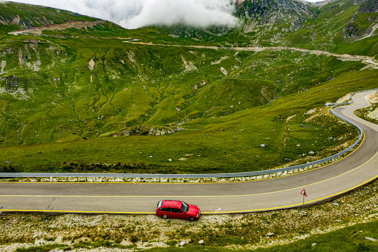 Rotes Auto steht vor einer Serpentine in den transilvanischen Alpen