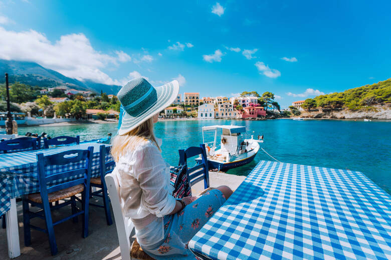 Frau sitzt in einem Restaurant in Griechenland und schaut auf das Meer