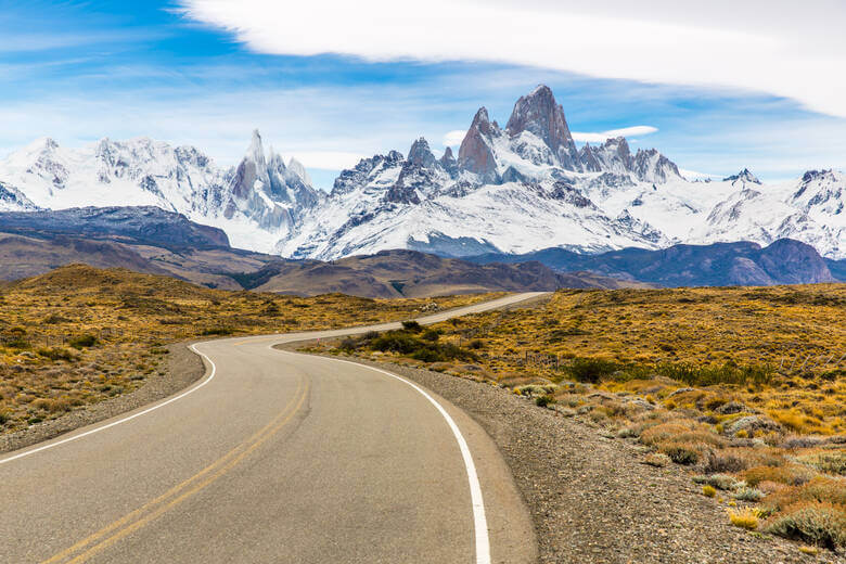 Straße in Patagonien mit schneebedeckten Begen im Hintergrund 
